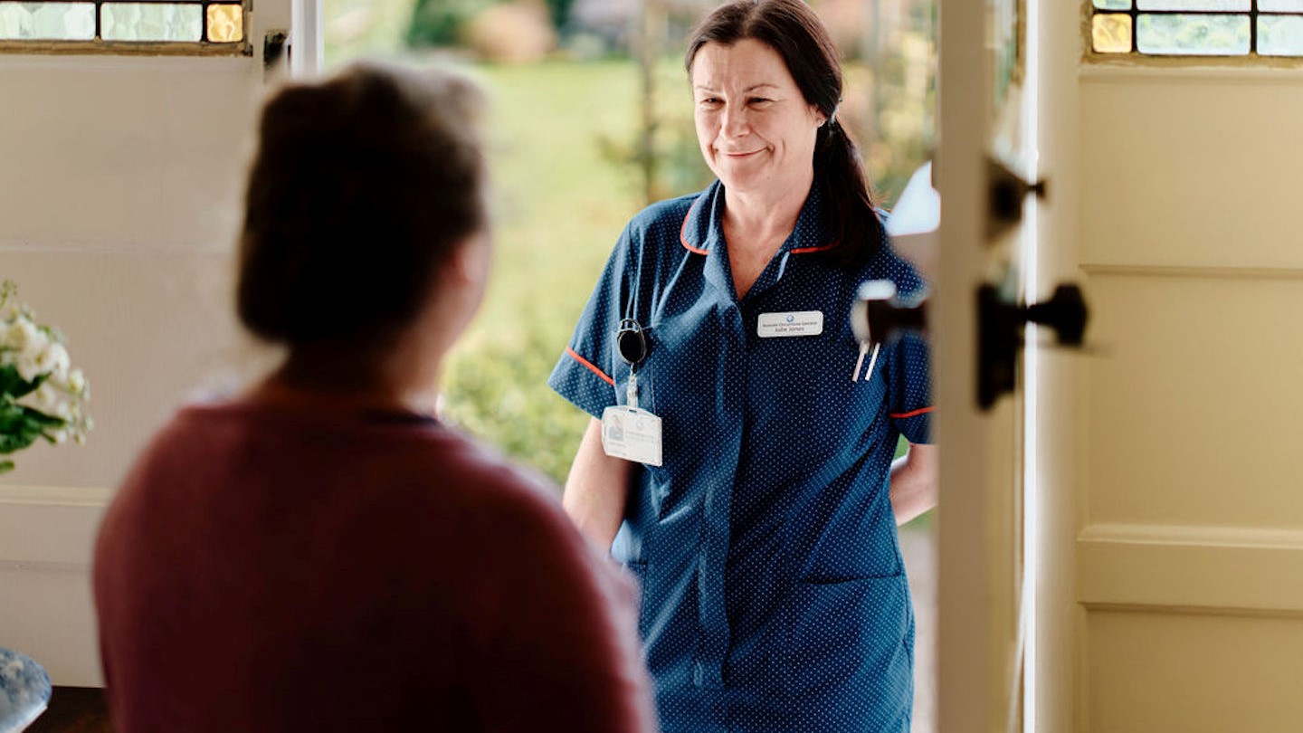 Image of community nurse at doorway visiting patient 